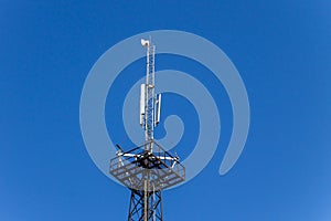 Metal tower with antennas for mobile cell phone communications against blue sky