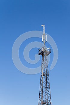 Metal tower with antennas for mobile cell phone communications against blue sky