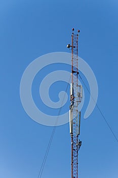 Metal tower with antennas for mobile cell phone communications against blue sky