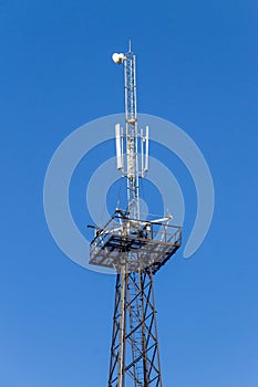 Metal tower with antennas for mobile cell phone communications against blue sky