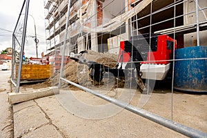 Metal trailer coupling of compressor peeks through wire fence on construction site