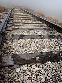 Train tracks leading around a curve and off into the fog