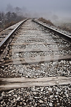 Train tracks leading around a curve and off into the fog