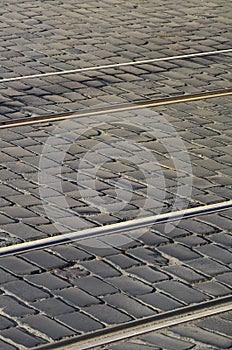 Metal tram rails in the middle of the road, laid out of a smooth paving ston