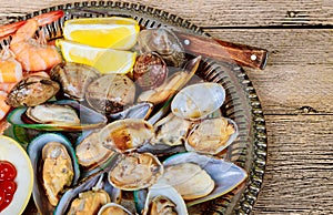 Metal tray with green mussels sauce over and Lemon