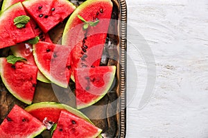 Metal tray with slices of ripe watermelon on white table