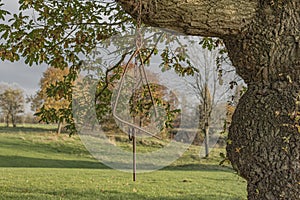 Metal triangle and striker hanging from a tree