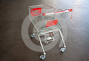 Metal trolley shopping basket at asphalt