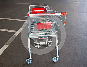 Metal trolley shopping basket at asphalt