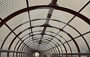 Metal tunnel bridge with wooden walkway.