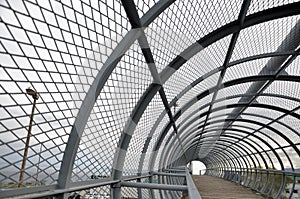 Metal tunnel bridge with wooden walkway.