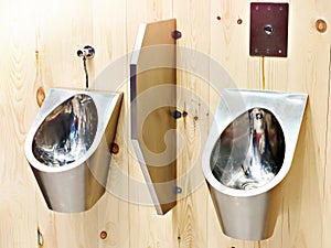 Metal urinals on wooden wall