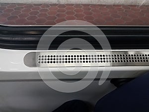 Metal vent with holes near window on public train transportation