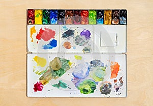 Metal watercolor palette box with colorful watercolor set on wood background