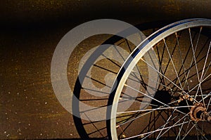 The metal wheel of the old bicycle with shadow on metal panel a