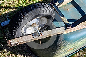 Metal wheelbarrow with a warn out tire, upside down ready to change the tire