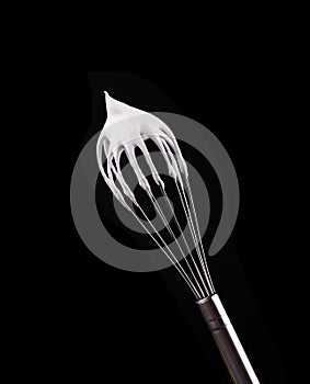 Metal whisk with whipped egg whites, isolated on black background. Clipping path.