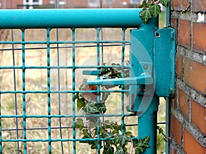 Metal wicket door handle in a wired green metal fence