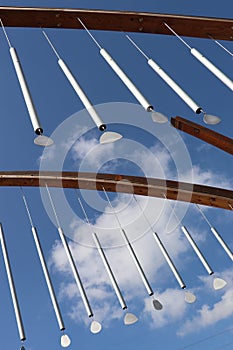 Metal wind chime sculpture against sky, two rows