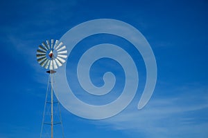 Metal windmill against blue sky