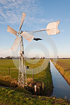 Metal windmill controls water level in ditch