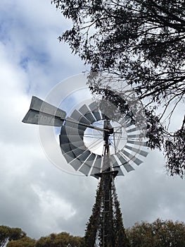 Metal windmill with trees and cloudy sky in Western Australia