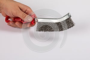 Metal wire brush with red plastic handle in a man& x27;s hand. White background