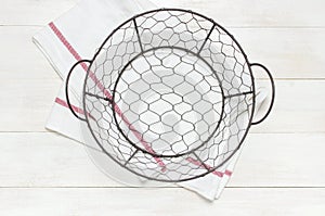 Metal wire empty Bowl Sieve and kitchen towel on rustic white wooden background top view flat lay copy space. Table setting,