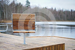 Metal with wooden cover modern chairs at the relaxation area in front of the lake