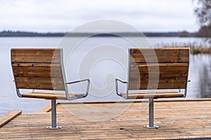 Metal with wooden cover modern chairs at the relaxation area in front of the lake
