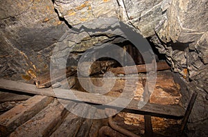 Metal and wooden timbering in abandoned old coal mine interior. Dangerous tunnels full of dirt and rusty equipment.