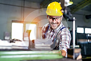 Metal worker turner operating lathe machine at industrial manufacturing factory.