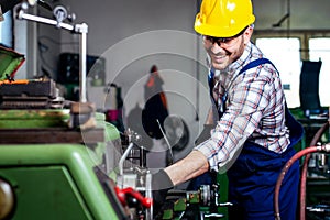 Metal worker turner operating lathe machine at industrial manufacturing factory. photo