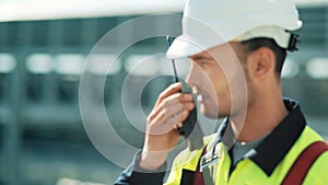 Metal worker in uniform and hard hat with walkie talkie medium close-up