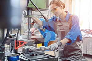 Metal worker woman operating drilling machine