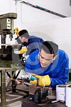 Metal workers in industrial workshop grinding