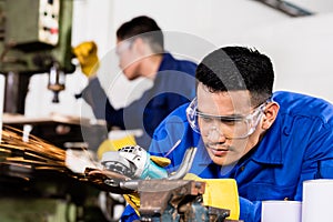 Metal workers in industrial workshop grinding