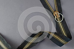 Metal zipper on gray background. Clasp with yellow prongs and black braid