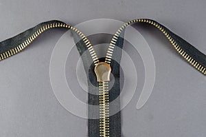 Metal zipper on gray background. Clasp with yellow prongs and black braid