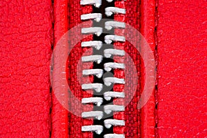 Metal zipper on intense red leather jacket or purse detail close up macro. The zipper is open between layers background.