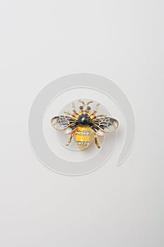Metallic brooch in shape of bee with gemstones imitation, pin on white background, bijouterie, jewelry close up