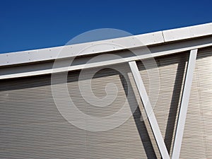 Metallic cladding on modern industrial building with steel girders and curved roof beam against a blue sky