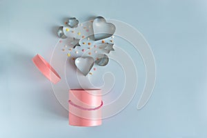 Metallic cookie cutters in heart shape flying out the pink gift box on blue background. Bonus and sale concept. Copy space