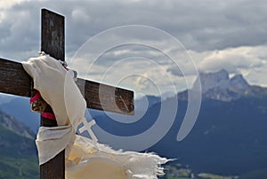 Metallic cross with white scarf and small white cross on the mountain peak top - mountains and clouds are in the background photo