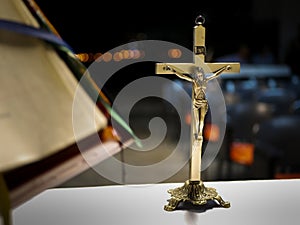 Metallic cross placed on an altar before a catholic mass at night with blurred background