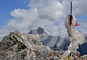 Metallic cross with white scarf from side on the mountain peak top - a series of mountain peaks and clouds are in the background photo