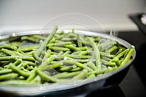 metallic frying pan full with frozen french green long string beans