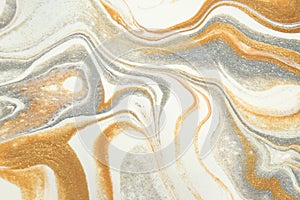 Metallic gold and shimmering silver swirl and dance in this abstract background. photo
