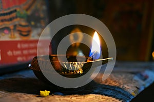 metallic golden glowing lamp or deepak or diya and yellow flame in dark background in night