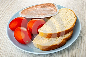 Metallic jar with liver pate, slices bread, tomato in plate on wooden table